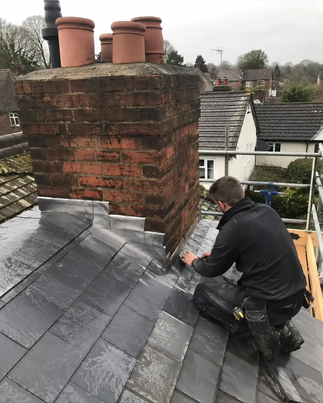 Hand-dressed lead flashing around a brick chimney on a slate roof