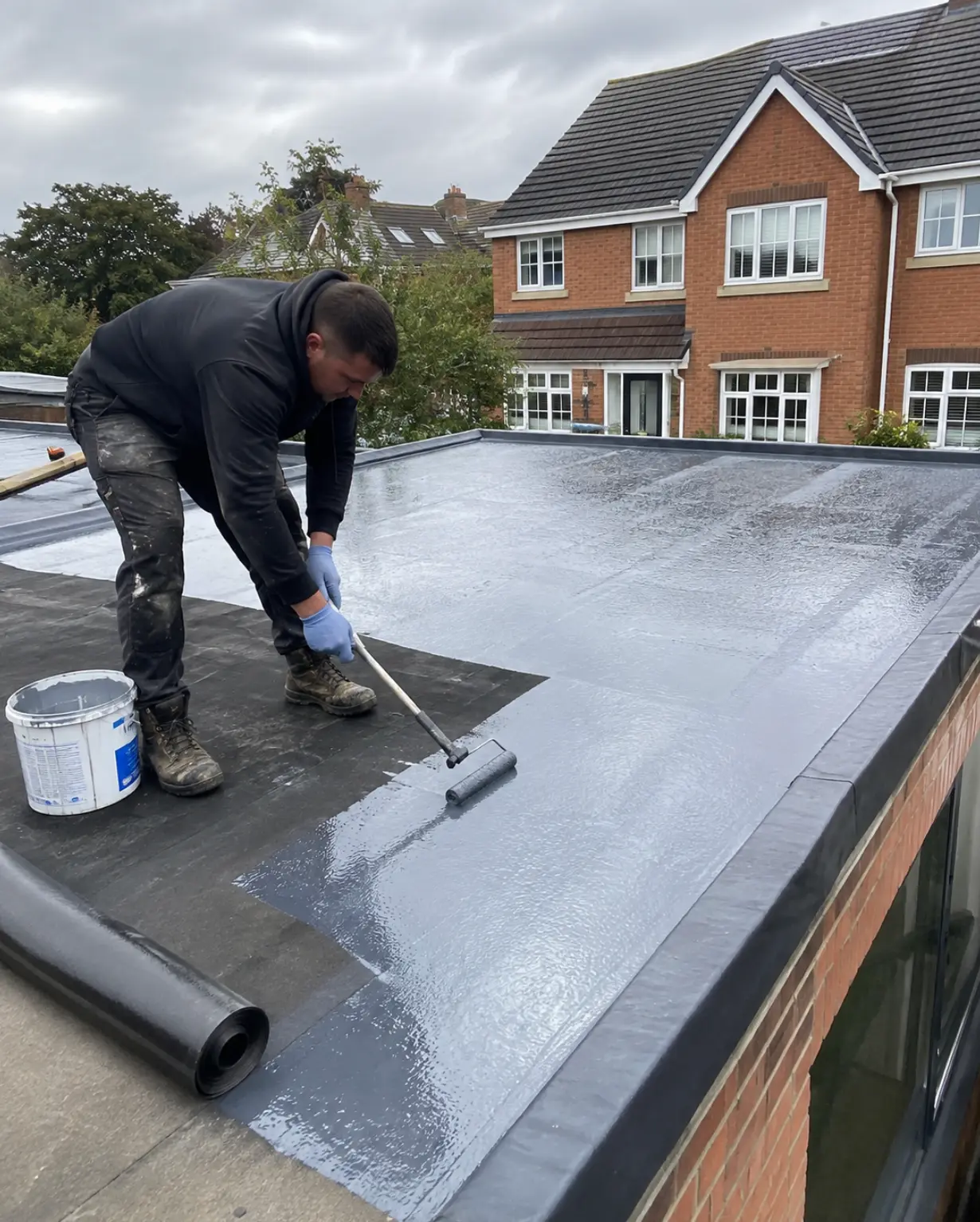 Roofer rolling primer onto a new EPDM flat roof on an extension